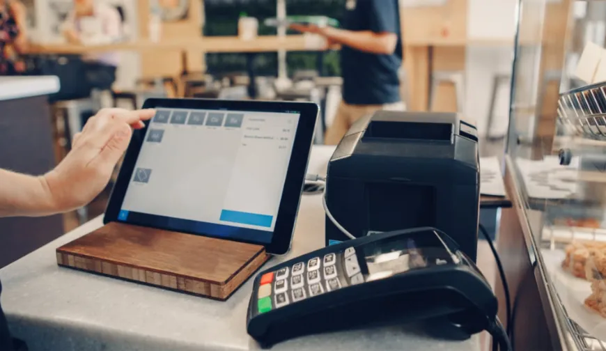 A point of sale system including a touchscreen monitor, card reader, and receipt printer on a counter in a retail environment.