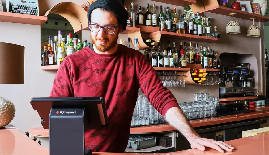Bartender using a Lightspeed point of sale system in a well-stocked bar.
